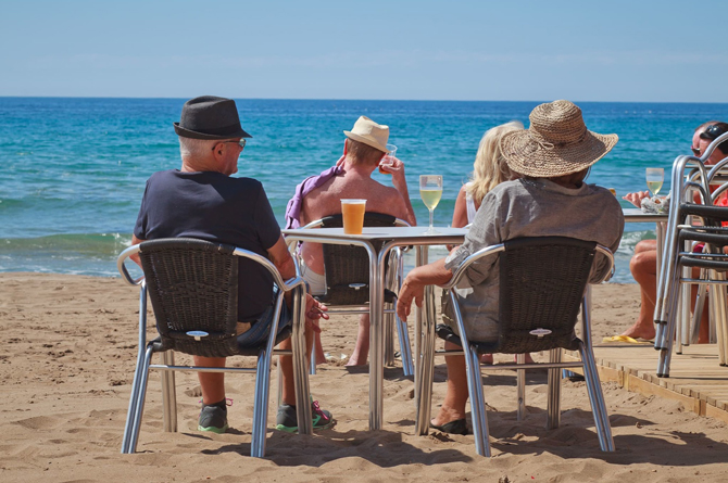Viajeros extranjeros sentados frente al Mediterráneo