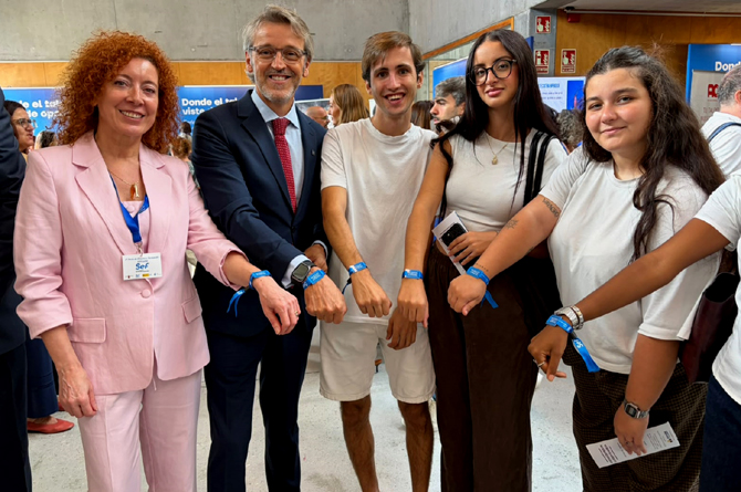 Luis Alberto Mar&iacute;n, la directora del SEF, Pilar Valero, y un grupo de asistentes a la V Feria de Empleo muestran las pulseras digitales que permiten entregar un CV de manera telem&aacute;tica